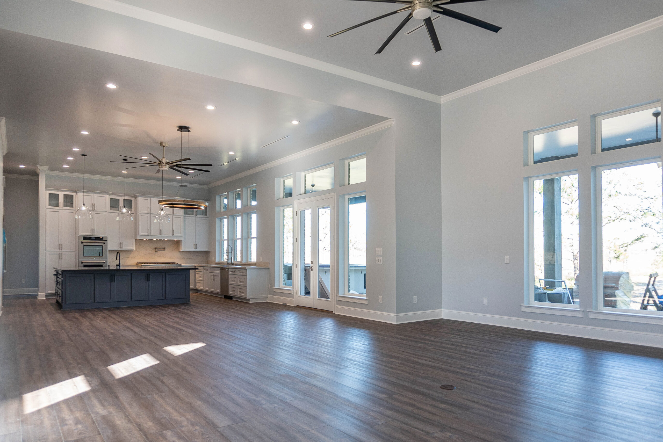 Boyt modern home interior gray tile floor blue kitchen island white cabinets ceiling fan circular light pendant lighting
