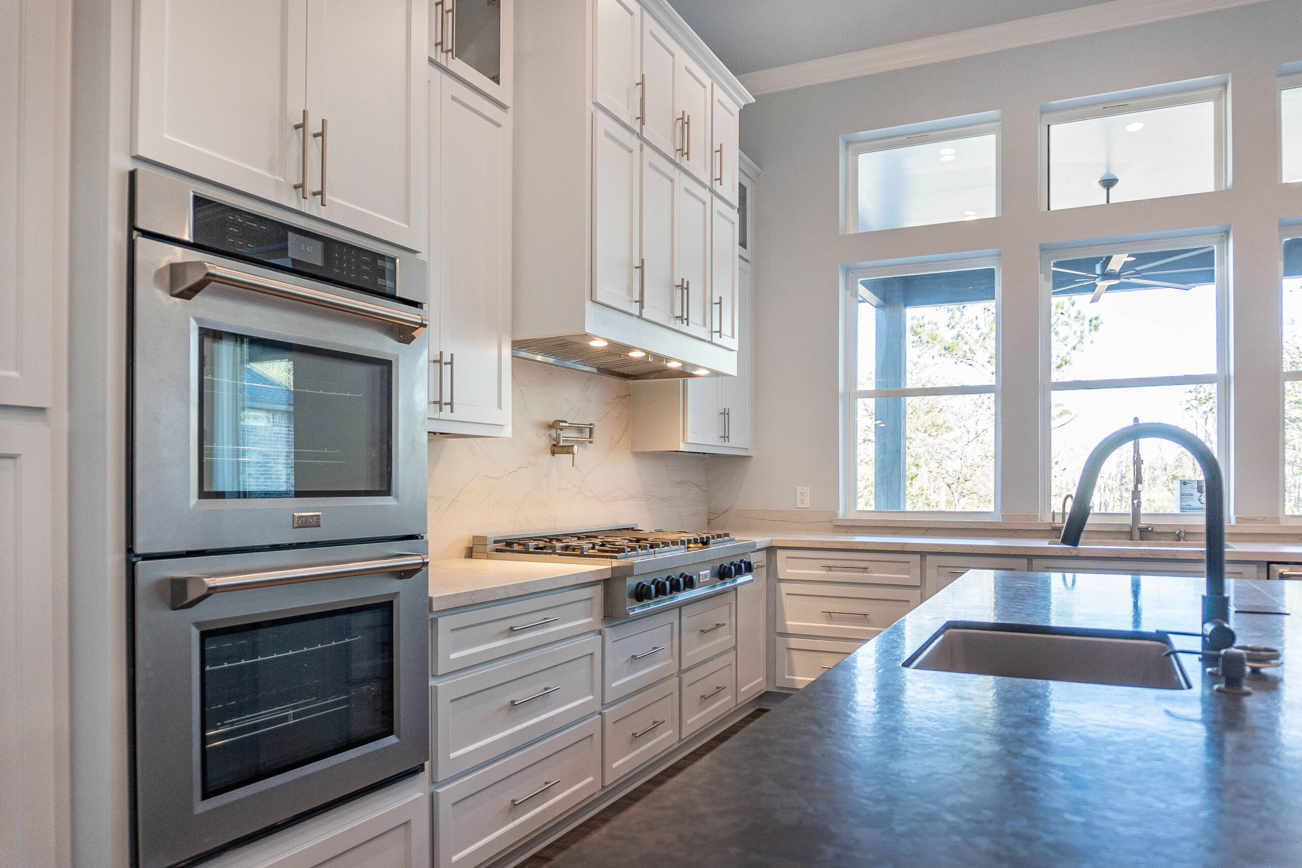 Boyt home modern kitchen white shaker style cabinets with gold hardware white marble backsplash built in double oven