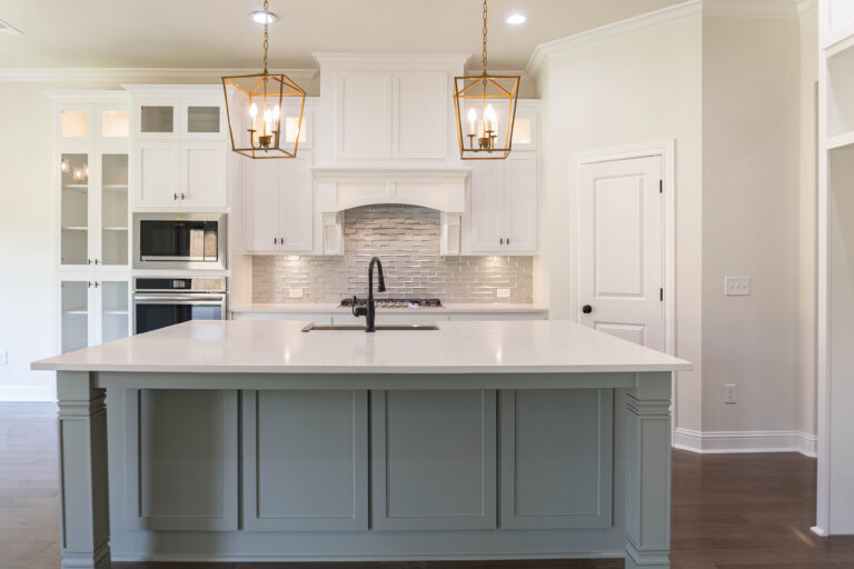 330 Hidden Grove new home lumberton texas kitchen with gold lantern style pendant lights over blue island with white marble counter top grey mirror tile kitchen backsplash