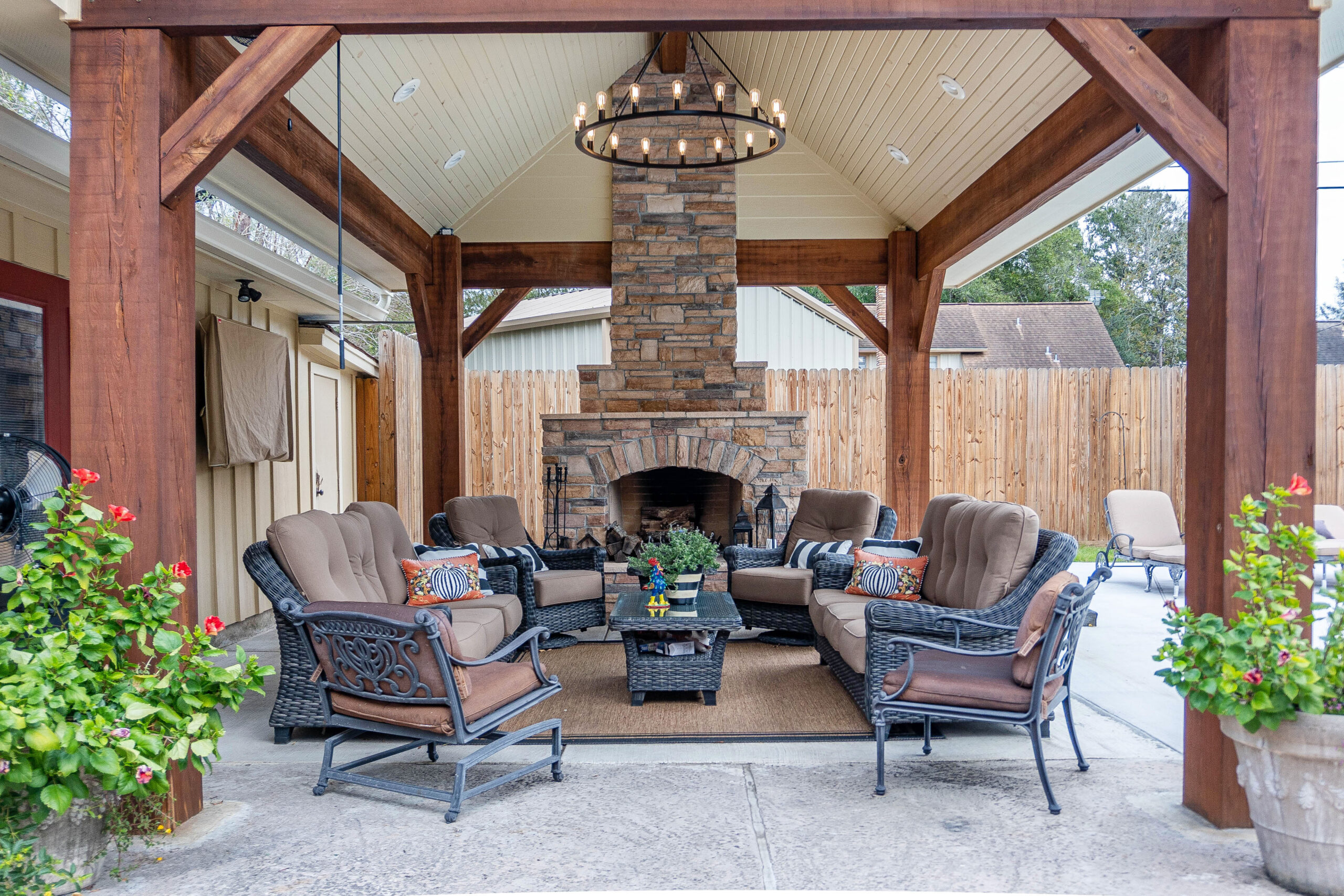 Continental classic home patio wicker patio furniture with cushions stone custom built fireplace stain wood columns beams