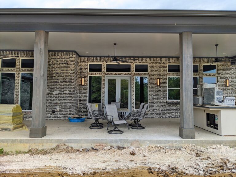 Boyt modern home exterior grey brown brick with blue trim metal rood gray stain wood post columns