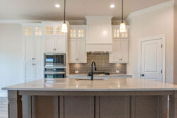 470 hidden grove court spec built home lumberton texas kitchen grey island with white marble counter tops two pendant lights above island white cabinets with window lights in top
